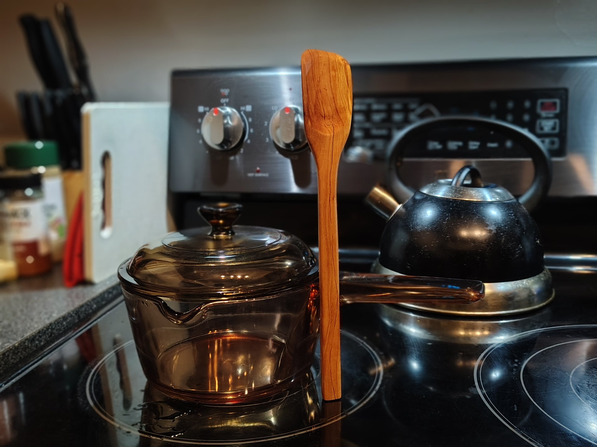 Small roux spoon standing next to saucepan on stove